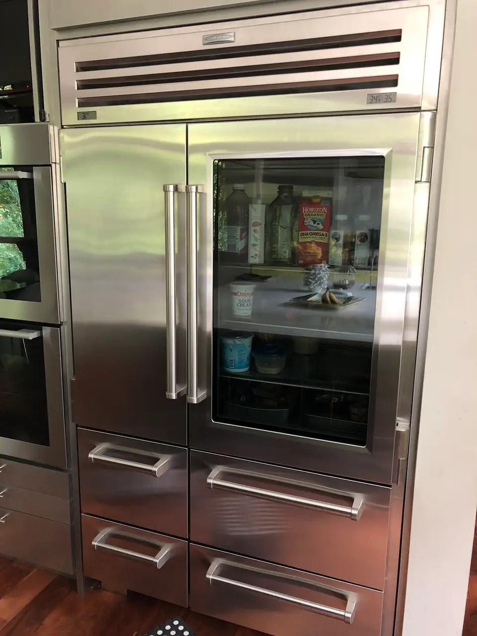 Sub-Zero PRO 48 stainless refrigerator with a glass door, next to a built-in wall oven